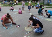 Рисуют дети на асфальте траву зеленую и дом…